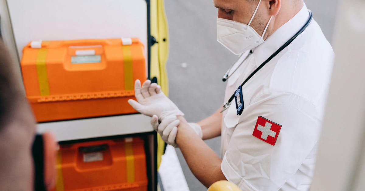 A paramedic putting on gloves next to emergency equipment inside an ambulance.